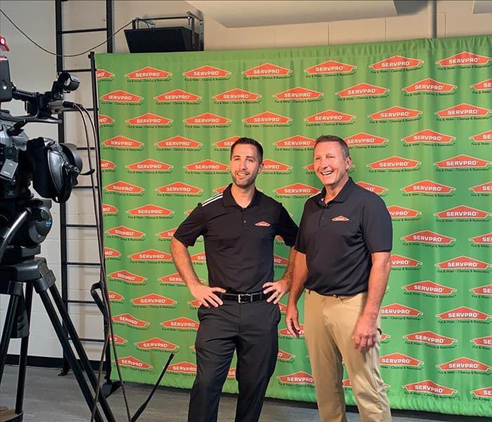 image of SERVPRO owners standing and smiling while on camera for the local news