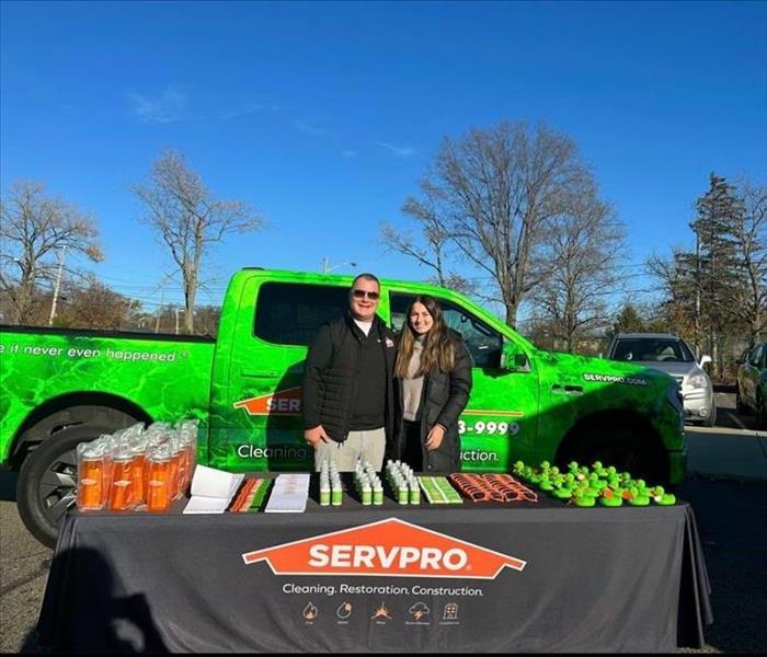 two people standing behind a table with a truck in the background