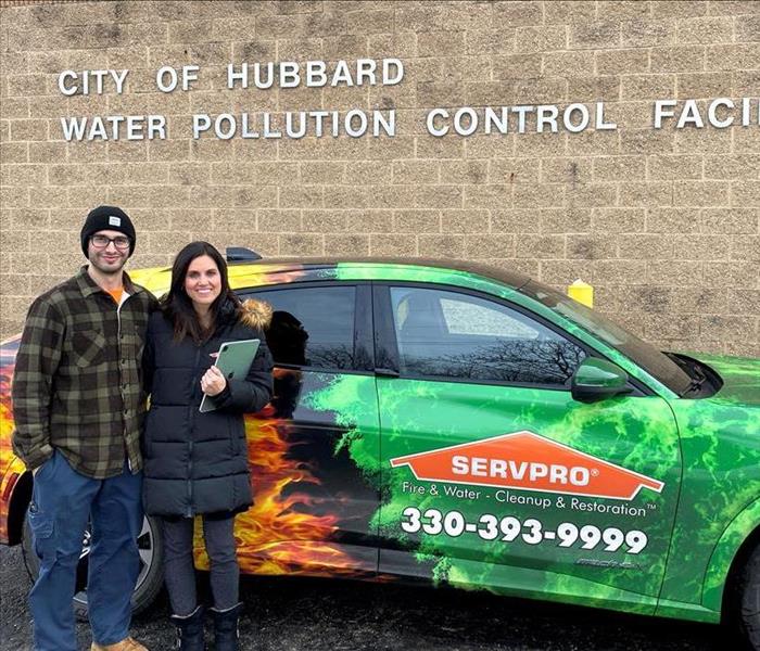 male standing with female SERVPRO employee in front of SERVPRO car